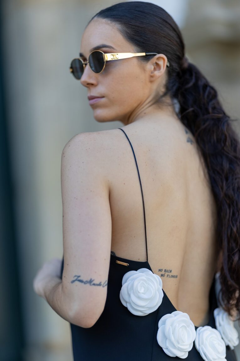 Mulher de óculos da céline com vestido preto com rosas de costas abertas